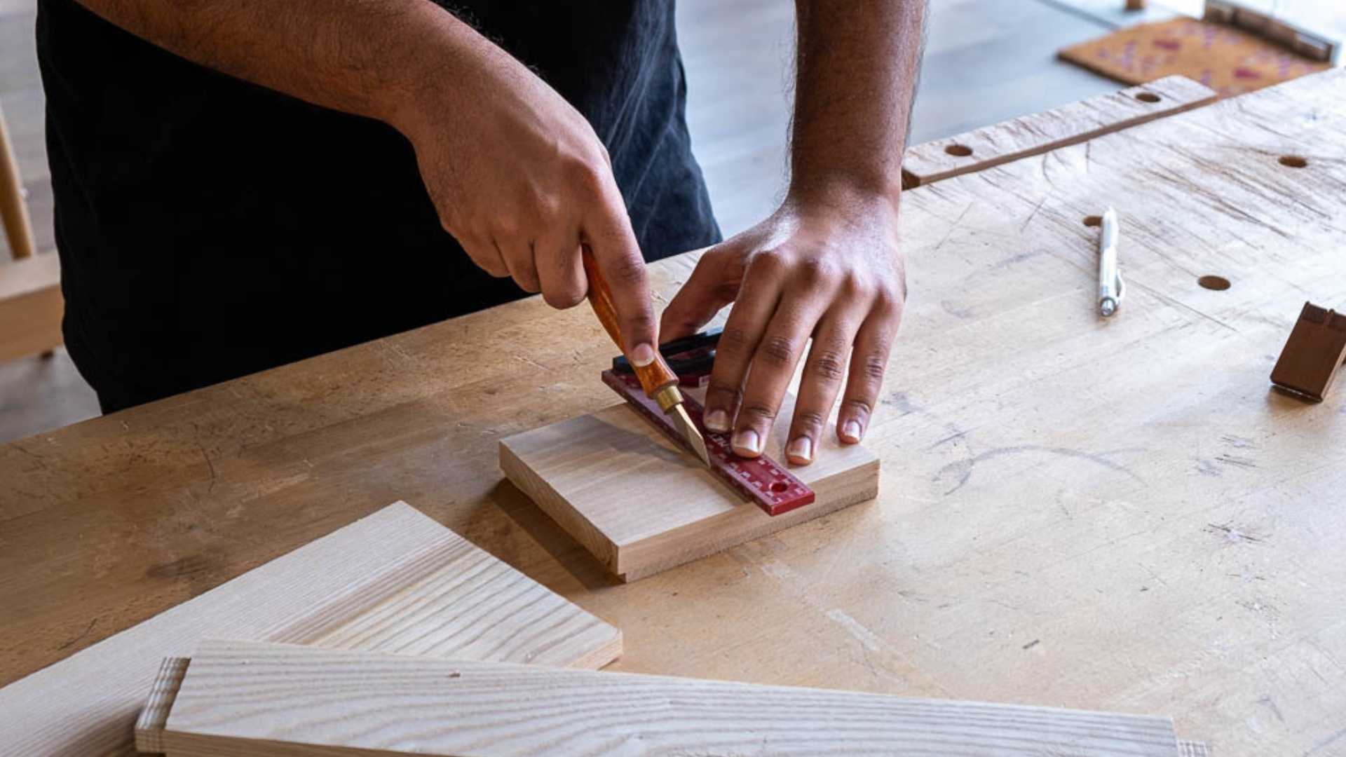 Precise joinery layout using a marking knife and square at The Makers Society woodworking bench.