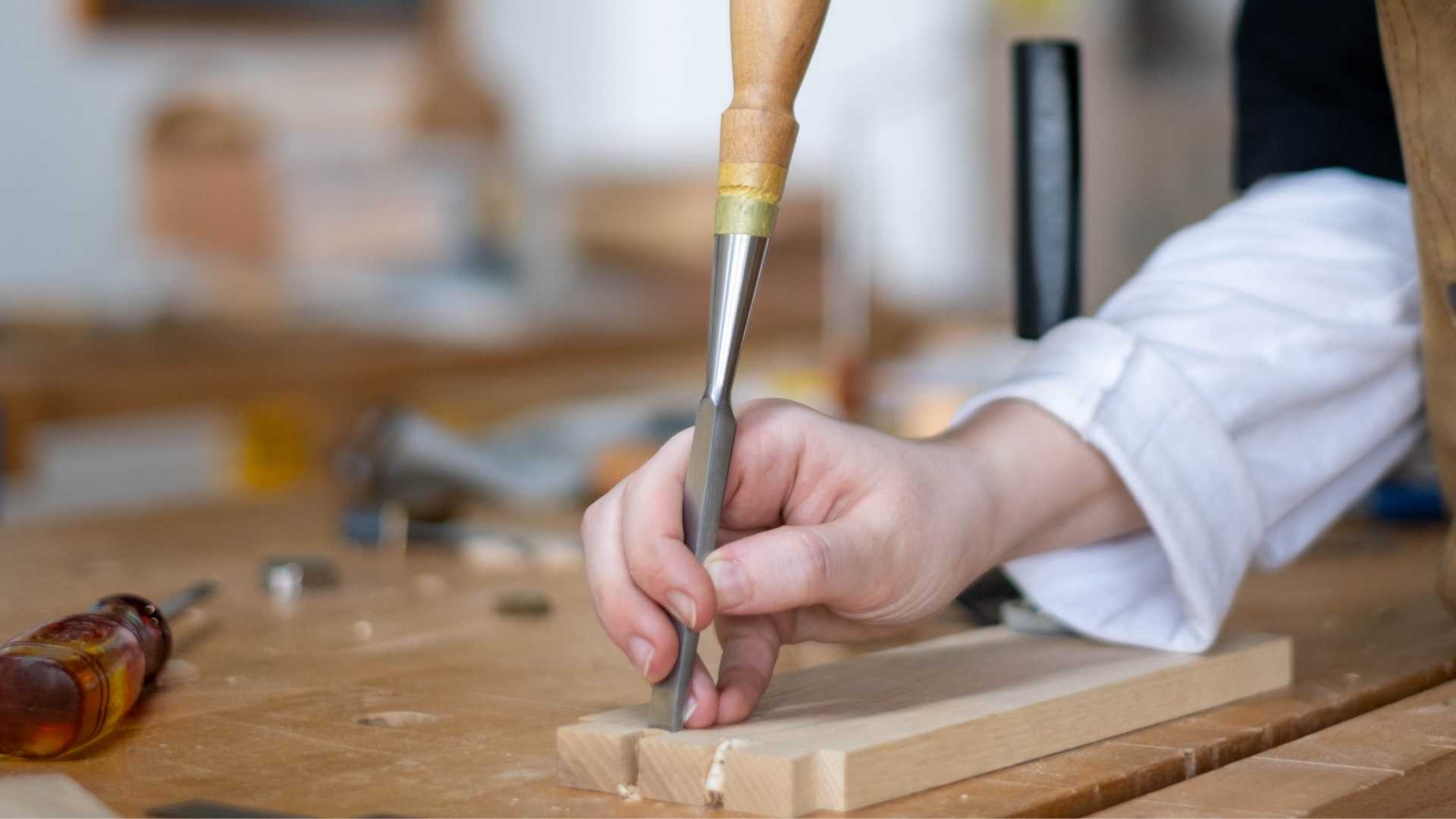 Pairing chisel being struck with a wooden mallet while chopping a deep rectangular mortise.