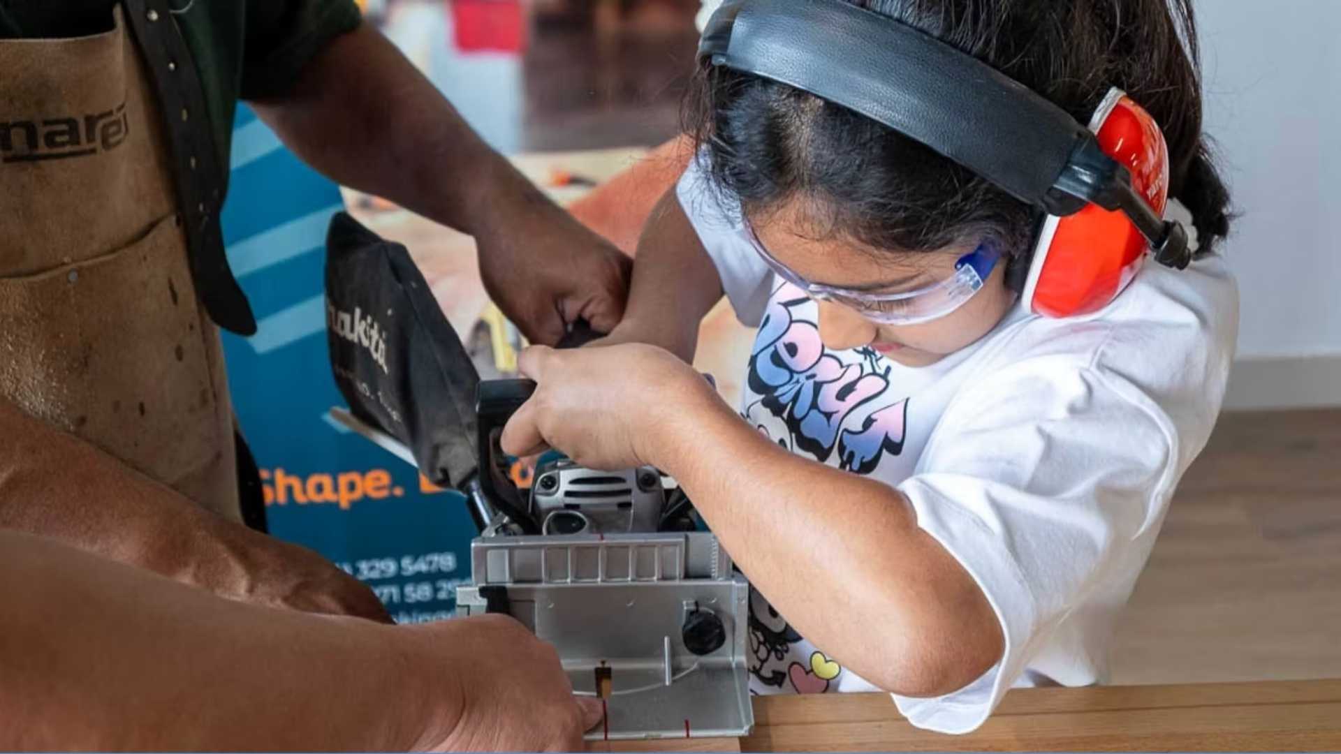 Teenager learning woodworking under instructor supervision while using professional tools safely