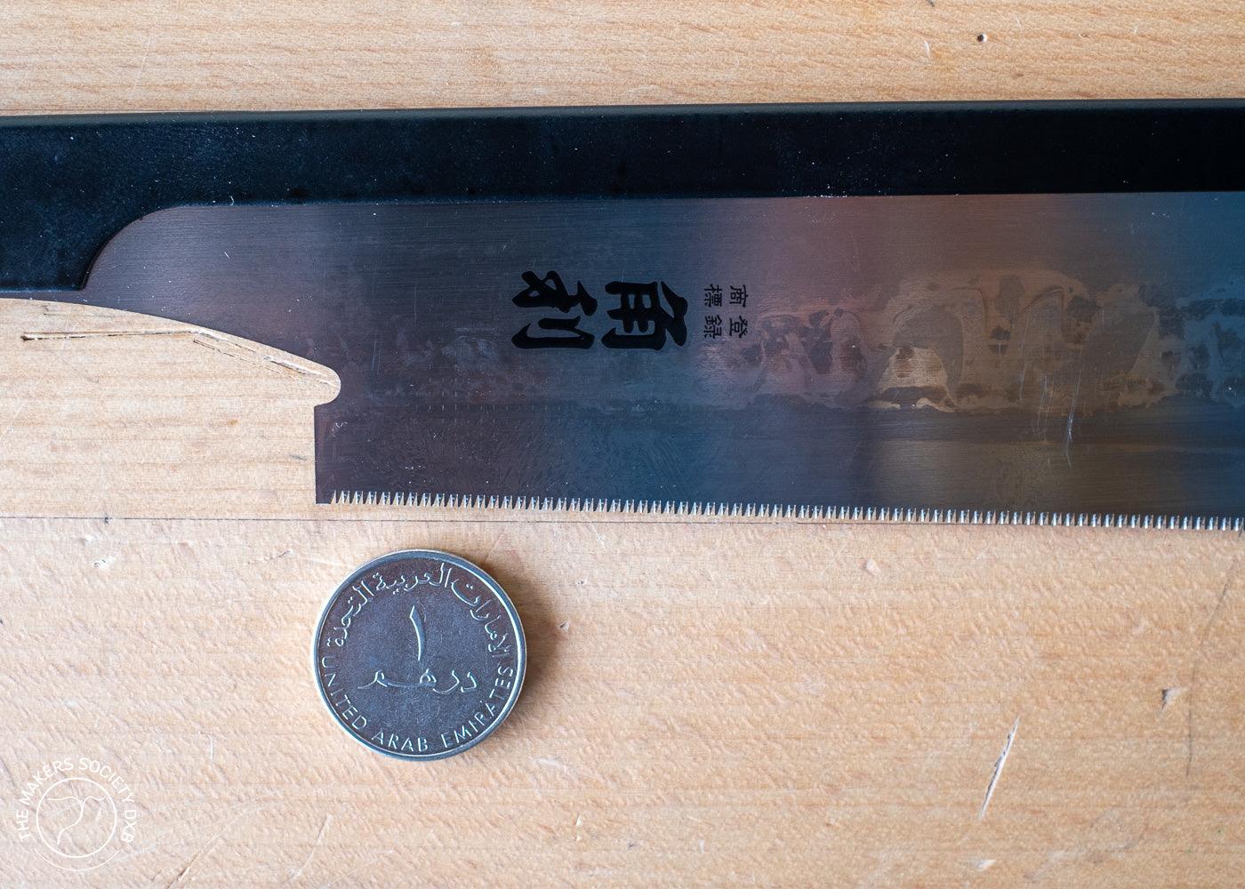 Kakuri Dozuki Saw 210mm Sakura Handle close up view with a coin to show the fine teeth ideal for joinery sold by The Makers Society Dubai