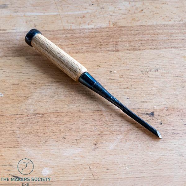 Kakuri 6mm Japanese wood chisel made of white steel with oak handle on wooden workbench