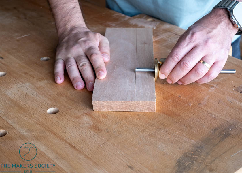 Woodworker using Luban marking gauge to scribe a line on hardwood board