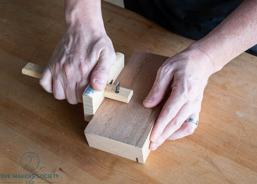 Person using a wooden tool on a wooden surface.