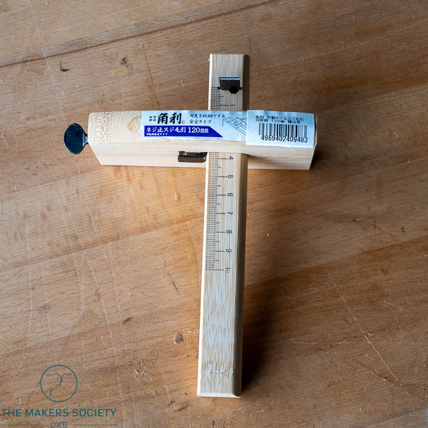 Wooden ruler with measurement markings on a wooden surface, branded 'The Makers Society'.