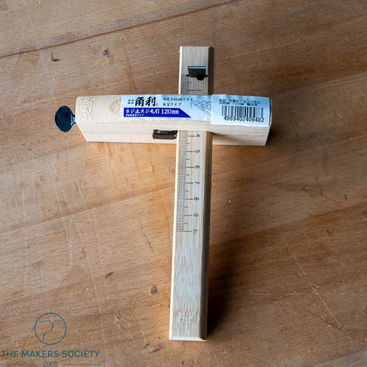 Wooden ruler with measurement markings on a wooden surface, branded 'The Makers Society'.