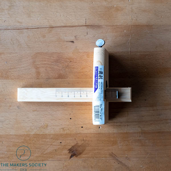 Wooden ruler with a small cylindrical object on a wooden surface branded