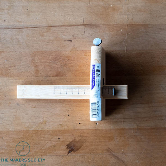 Wooden ruler with a small cylindrical object on a wooden surface branded