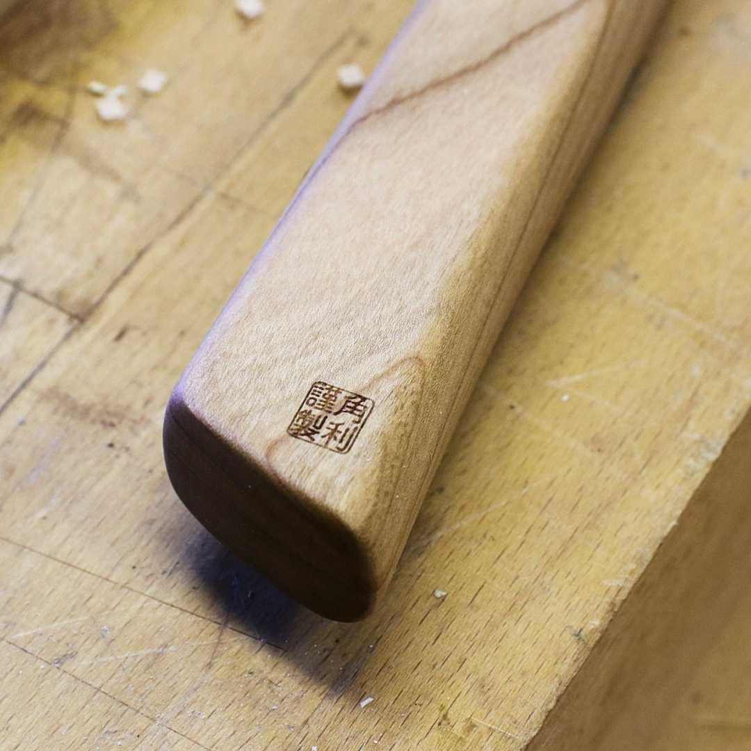 Kakuri Sakura precision tenon saw wooden handle close-up with Japanese brand stamp on workbench