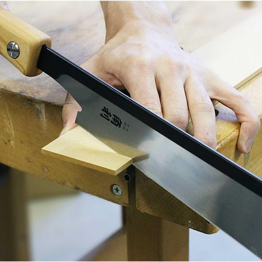 Close-up of hand using Kakuri Sakura Japanese precision tenon saw cutting wood at woodworking bench