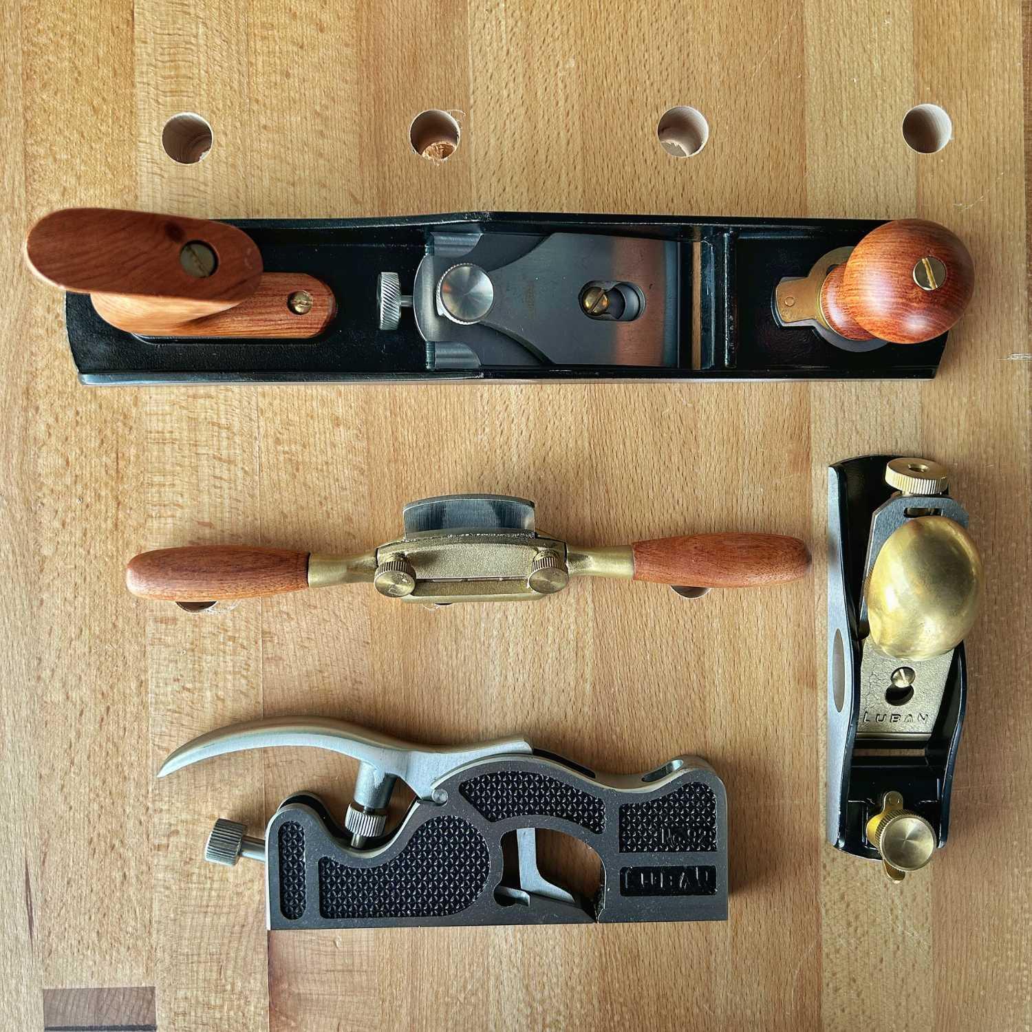 Set of four woodworking hand planes with wooden handles on a wooden workbench