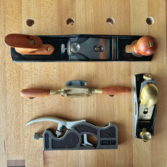 Set of four woodworking hand planes with wooden handles on a wooden workbench