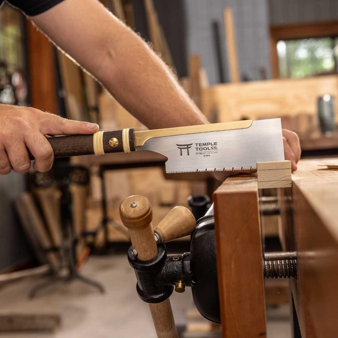 Hand using Temple Tool Co. 150mm Dozuki pull saw on wood block in woodworking bench