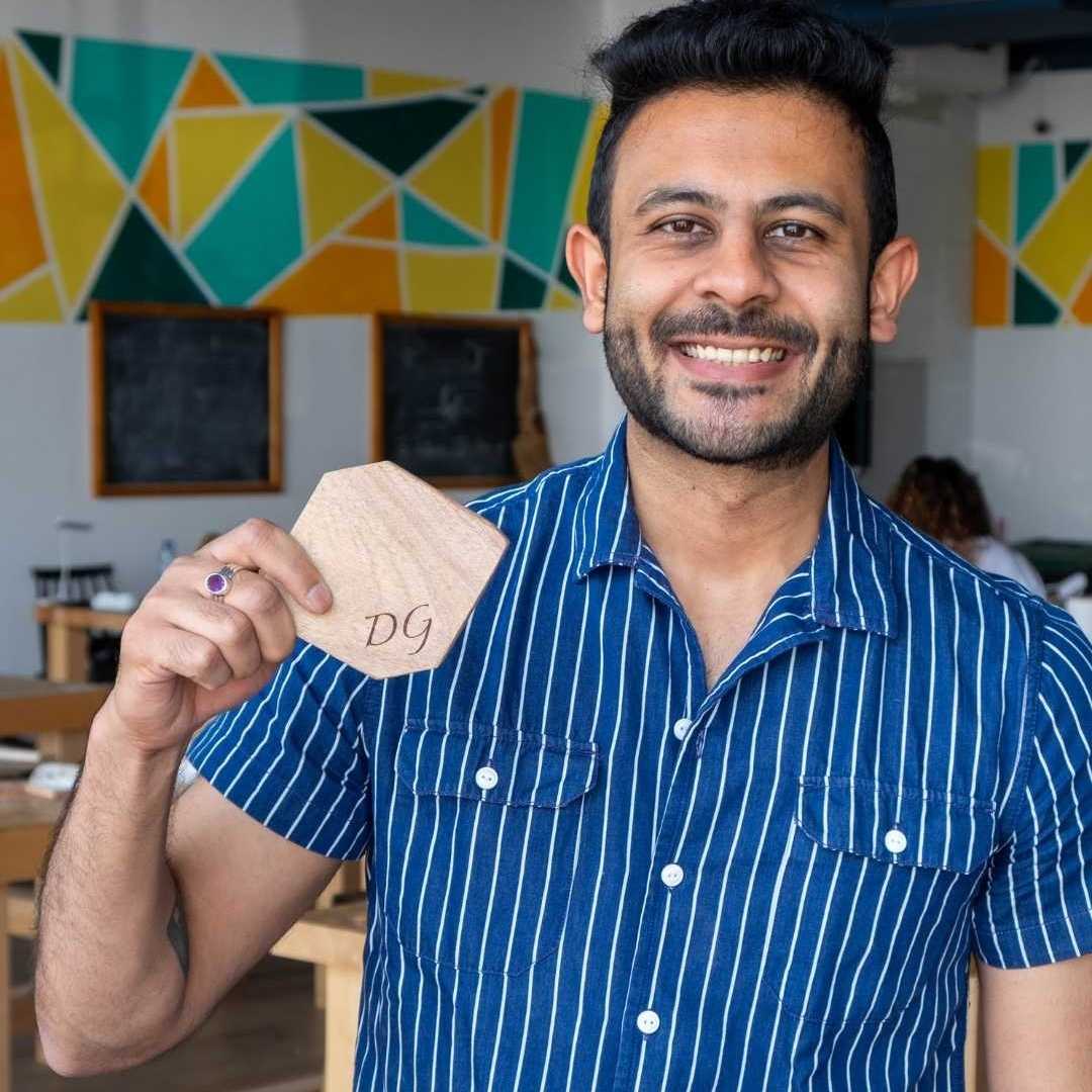 Man holding a wooden product with initials in a casual setting