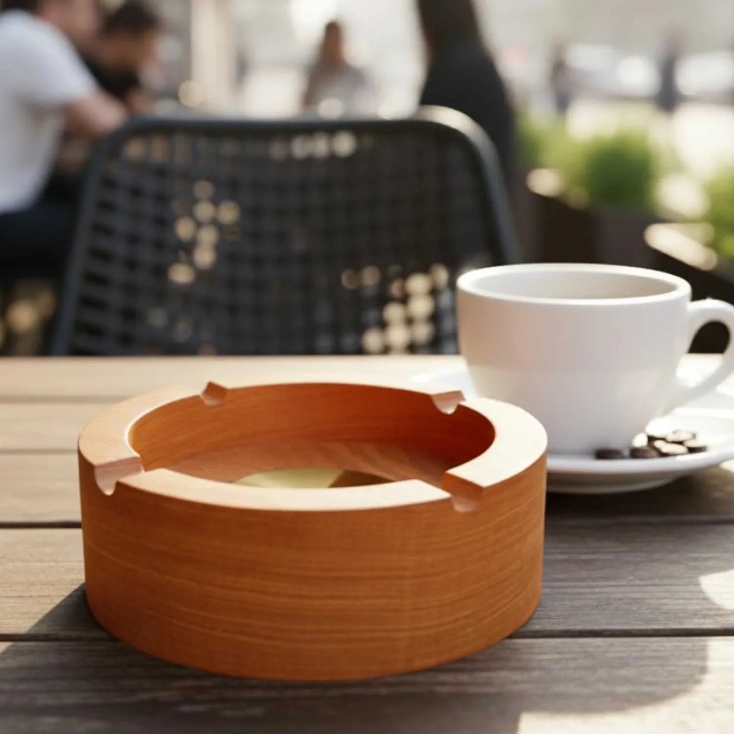 Round Zelkova Japanese wooden ashtray on outdoor table next to white coffee cup and saucer